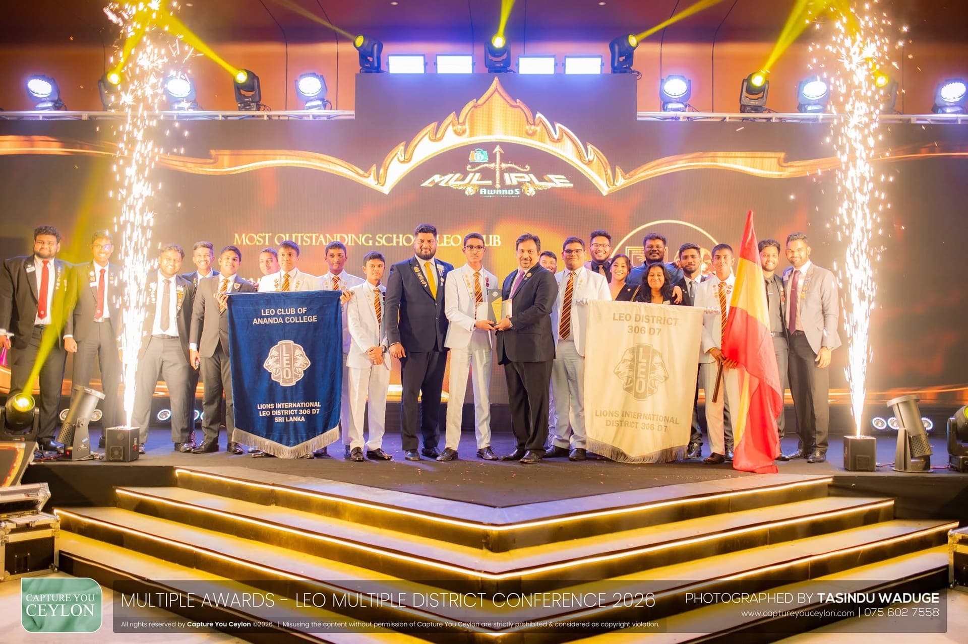 The club on stage receiving Most Outstanding School Leo Club at the Leo Multiple District Conference, club and district banners raised between sparklers